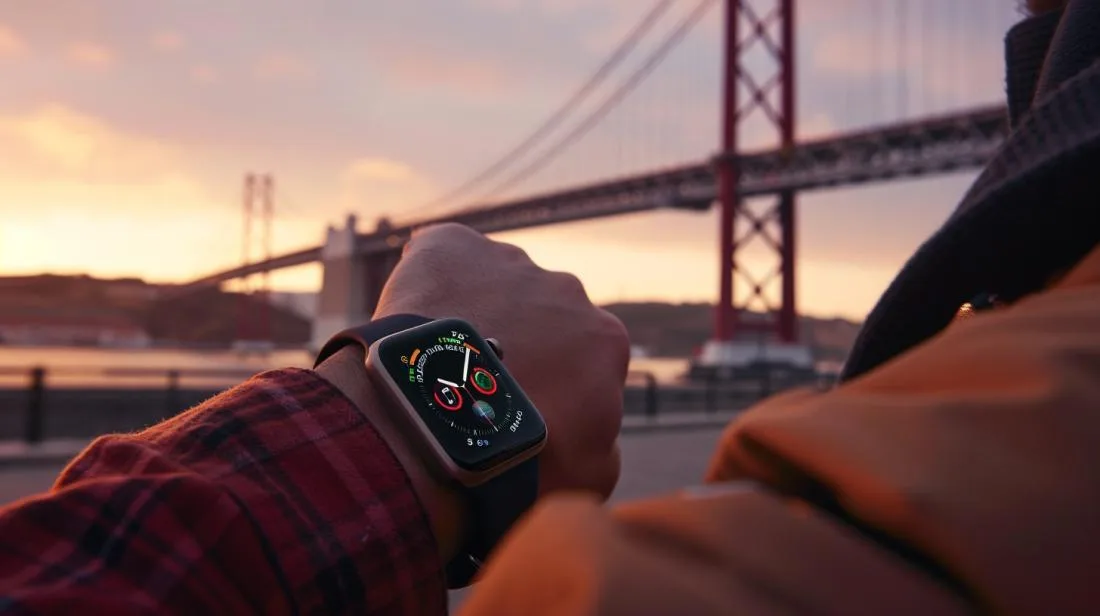 Pessoa sofisticada verificando notificações no Apple Watch, com a Ponte 25 de Abril ao fundo.