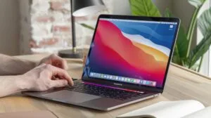 Fotografia hiper-realista de um MacBook Pro em um ambiente de escritório moderno e aconchegante.